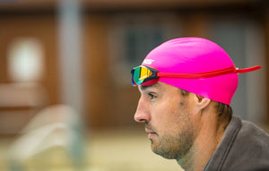 Person wearing a pink swim cap and SWANS Ascender goggles with a blurred background